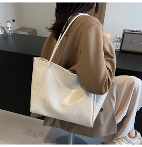 Dettaglio della borsa tote color crema con logo VVGONGZYD a rilievo e spalline fini