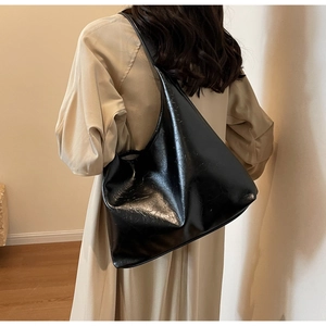 Vue détaillée du sac hobo en cuir PU noir brillant porté à l'épaule par le mannequin