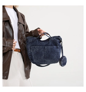 Détail d'un sac à main en denim bleu foncé avec poches avant et petit porte-monnaie rond