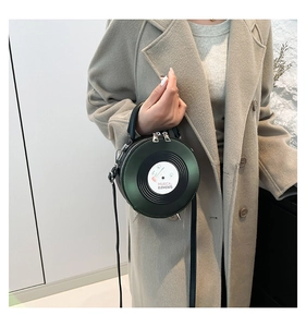 Detail of green vinyl record shaped PU leather bag with metal feet held by model