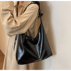 Vue latérale d'un sac hobo noir brillant en similicuir porté par un mannequin