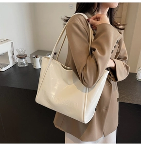 Dettaglio della borsa tote in pelle crema con scritte in rilievo e texture moderna