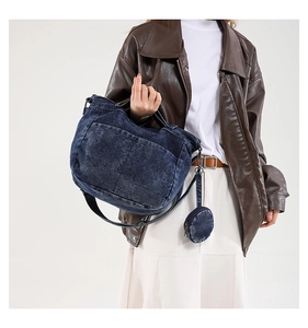 Détail d'un sac cabas en denim bleu délavé avec charm porte-monnaie sur un mannequin femme