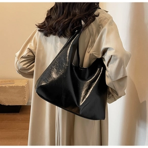 Détail de la texture en cuir ciré brillant sur un grand sac porté épaule noir
