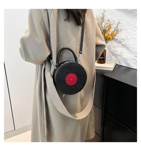 Detail of round vinyl record style crossbody bag in black PU leather shown on model