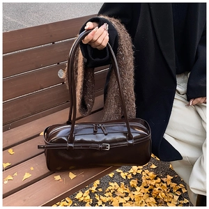 Detailed close-up of a vintage dark brown glossy shoulder bag on a wooden bench