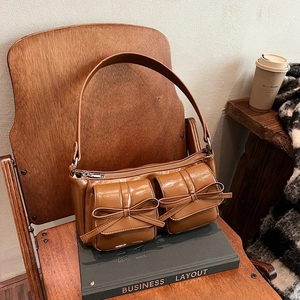 Vintage brown PU leather underarm bag with bow-knot pockets on a wooden chair