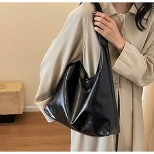 Détail montrant la texture du cuir brillant et le design plissé doux du grand sac hobo