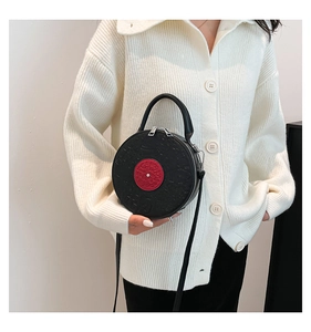 Detail view of the black retro record-shaped PU leather crossbody bag worn by a model
