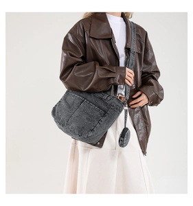 Détail d'un sac bandoulière en denim délavé gris avec porte-monnaie rond et grande poche