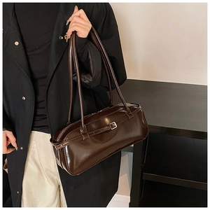 Detail showing the glossy dark brown leather rectangular bag with metallic buckle accent