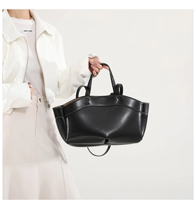 Detail view of the black leather tote bag with white stitching and semi-circular design
