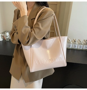 Dettaglio della borsa tote rosa chiaro con lettere goffrate VVGONGZYD e finitura lucida