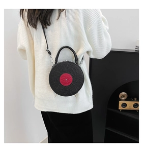 Detail view of a black vinyl record shaped PU leather bag with red center and embossed patterns