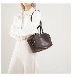 Detail view of dark brown leather tote bag with contrast stitching and metal hardware