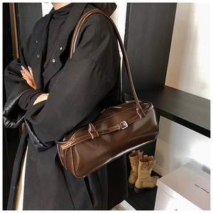 Detailed close-up of dark brown glossy PU leather shoulder bag on model in studio