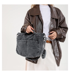 Détail d'un sac cabas en jean gris délavé avec poches et petit pendentif porte-monnaie