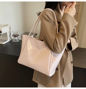 Vista laterale dettagliata della borsa tote in pelle verniciata rosa con lettere a rilievo