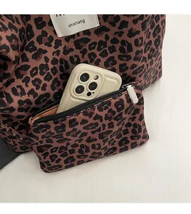 Detail view of leopard print canvas tote bag accessory pocket with a smartphone inside