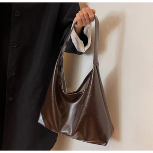 Détail de la texture en similicuir marron foncé brillant sur un grand sac à bandoulière