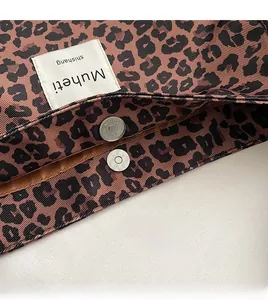 Detail of silver magnetic closure and leopard print canvas texture on a tote bag