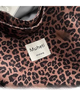Detail view of pink leopard print canvas texture with a white woven brand logo patch