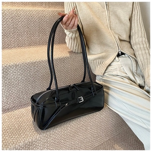 Detail of glossy black faux leather shoulder bag with metal buckle and zipper closure