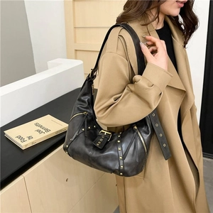 Détail du sac croissant en cuir noir avec clous dorés et bandoulière réglable