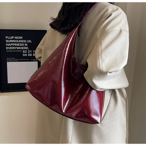Détail d'un sac cabas en cuir verni rouge foncé brillant avec texture plissée