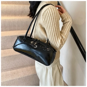 Macro detail of black PU leather shoulder bag featuring metal buckles and long straps