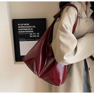 Détail du grand sac cabas en cuir verni rouge bordeaux porté à l'épaule par un mannequin