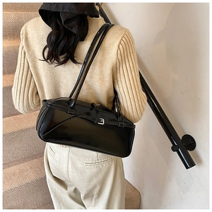 Close-up of stylish black glossy patent leather baguette bag with silver buckle and thin straps