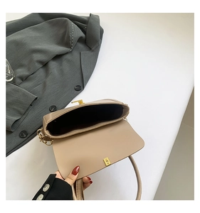 Close-up of beige leather crossbody bag with gold hardware buckle and chain detail