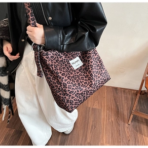 Detail of stylish leopard print tote bag featuring branded label and soft fabric texture