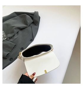 Detail view of white leather crossbody bag with magnetic closure and golden chain
