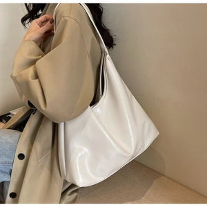 Grand sac hobo blanc cassé brillant porté avec un trench-coat classique élégant