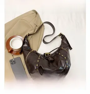 Détails d'un sac demi-lune vintage marron foncé avec rivets dorés et fermetures éclair