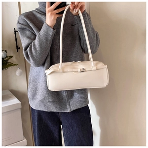 Model wearing a minimalist cream rectangular baguette bag with a matte leather finish