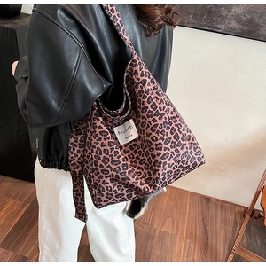 Fashionable leopard print tote bag with brand label shown on model in street style view
