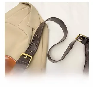 Détail de la bandoulière large réglable avec boucle dorée vintage sur un sac marron