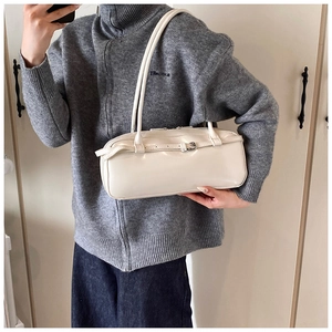 Close-up of cream rectangular baguette bag with slim shoulder straps and silver buckle detail