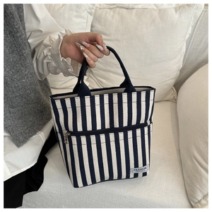 Detailed shot of blue and white striped canvas tote bag with front zipper pocket and logo