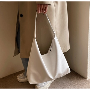 Détail macro du grand sac porté épaule en cuir PU blanc au design incurvé minimaliste