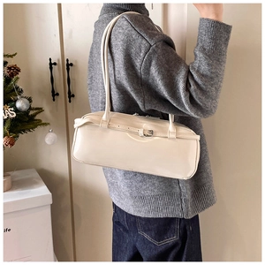 White glossy leather baguette bag styled on shoulder with minimalist rectangular design