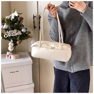 Close-up of cream-white baguette bag with decorative buckle strap in a cozy setting
