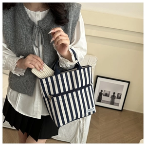 Detail view of blue and white striped canvas tote bag with front zipper and fashion tag