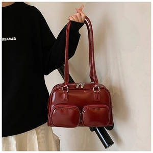 Detailed view of dark red glossy patent leather shoulder bag with double zip front pockets