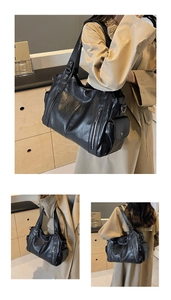 Detail view of large black oil-wax leather tote bag with metallic zippers and side pockets