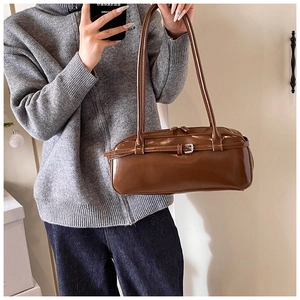 Detail shot of a dark brown PU leather baguette bag with silver buckles and slim handles