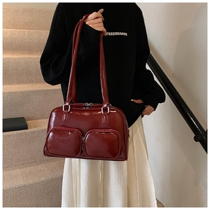 Detail of burgundy patent leather shoulder bag with two front pockets on a model